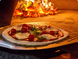 Traditional style pizza going into a hot pizza oven