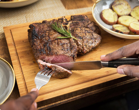 Elegant knife cutting T-Bone with potato side